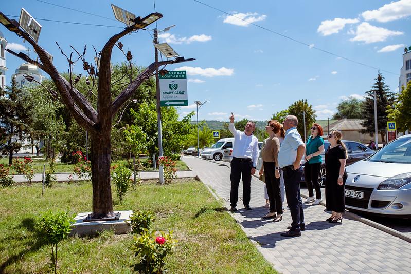 A group of people standing on a sidewalk

Description automatically generated